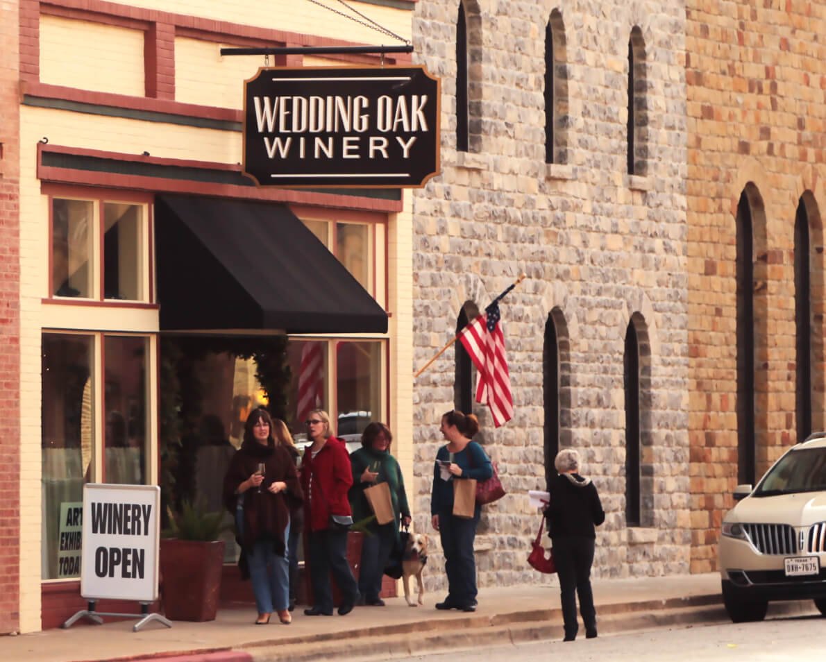 The Wedding Oak Winery storefront in San Saba with a WINERY OPEN sign on the sidewalk