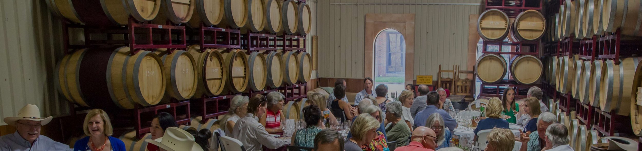 Long tables set for a wine dinner among the barrels