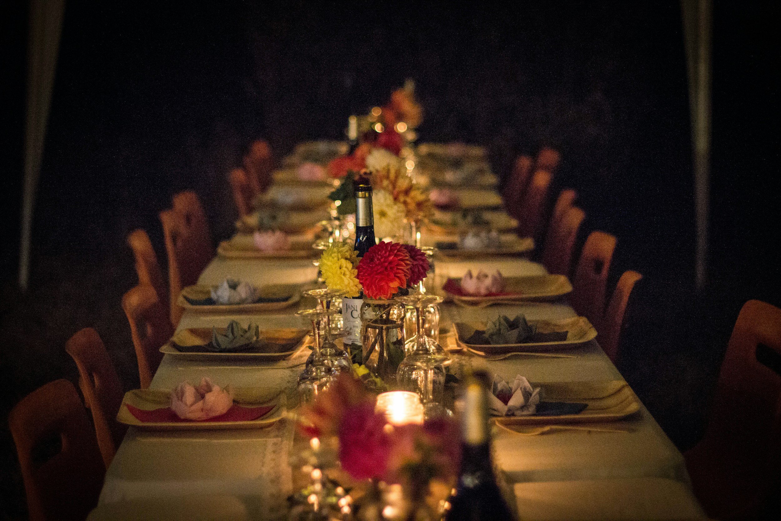 A candlelit dinner table set with flowers and wine